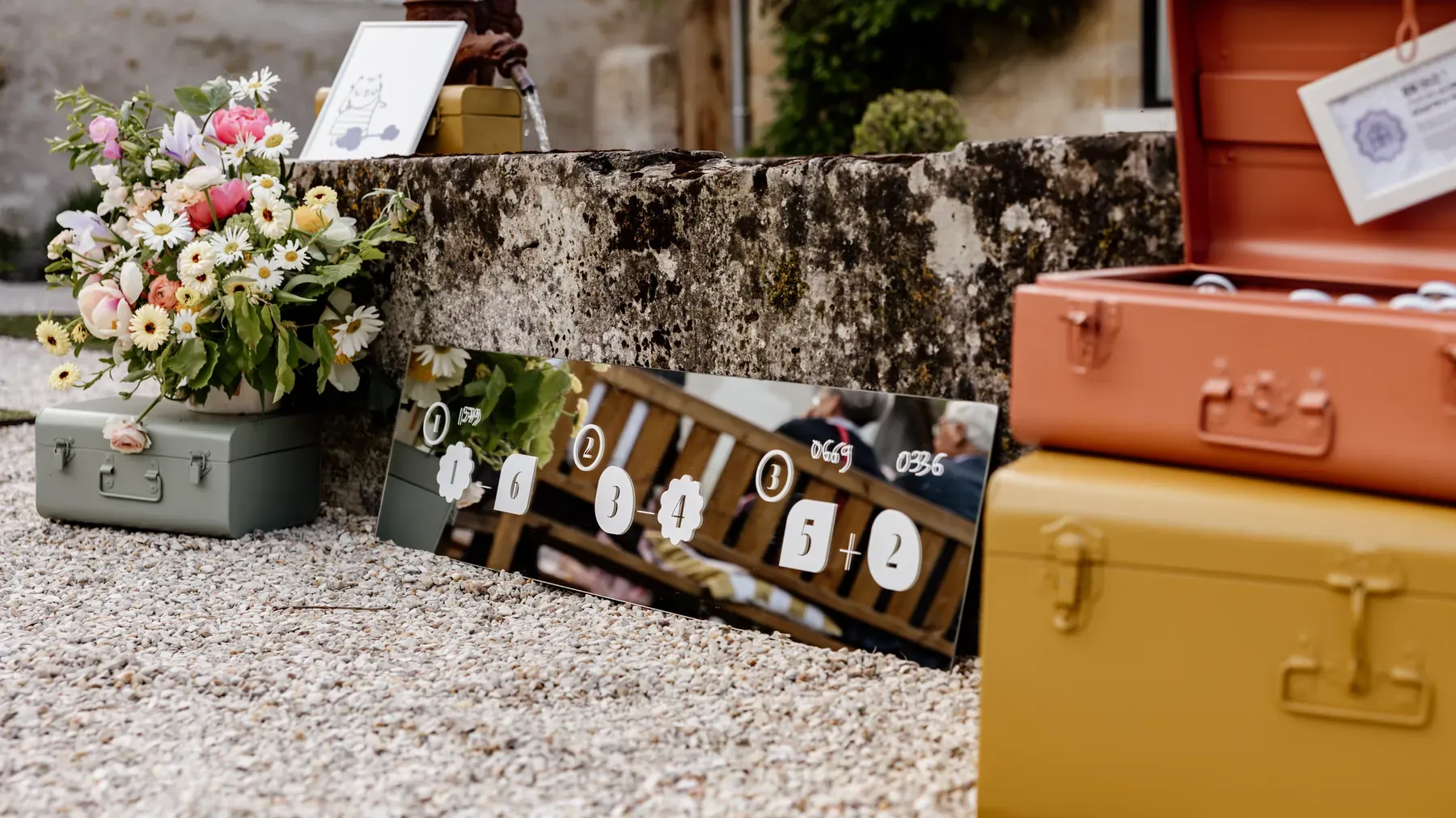The escape game set up in the courtyard: painted trunks, a mirrored clue panel and the first floral arrangement