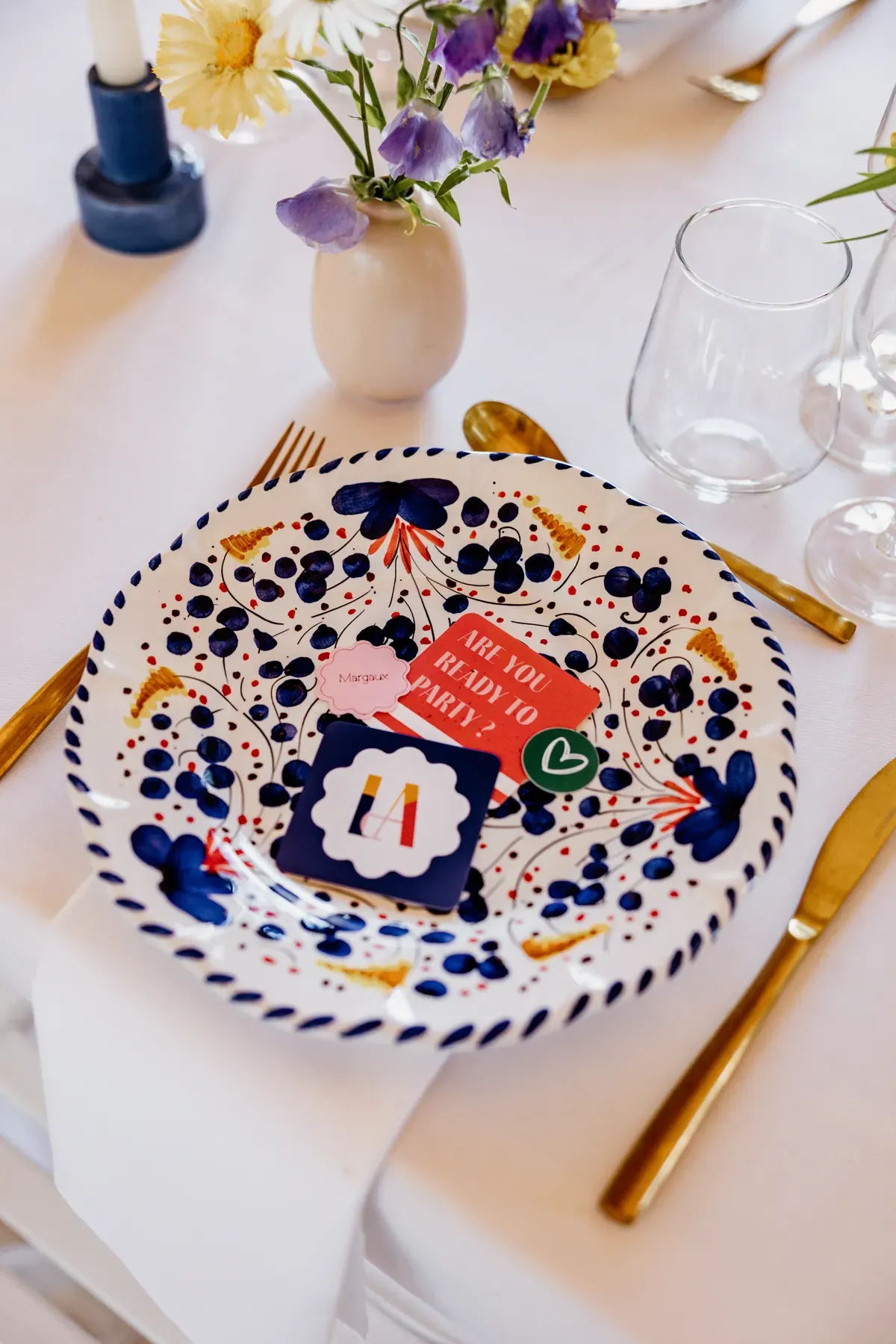 Place setting built on the patterned plate, with a monogram coaster and printed cards laid on it