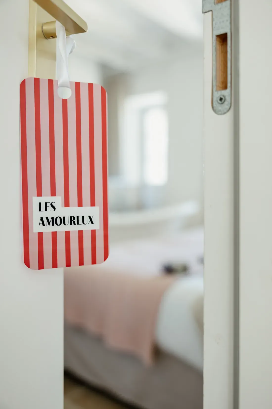 Striped door tag hanging from a bedroom handle, naming the room in the identity's display type